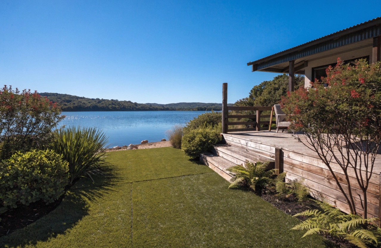 a-beautifully-landscaped-backyard-in-a-lakeside-au Synthetic grass installation in a lakeside Lake Macquarie backyard with timber deck and garden borders